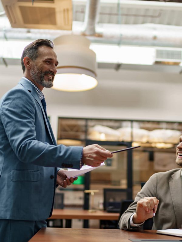 mature-business-coach-or-speaker-make-flip-chart-presentation-to-diverse-businesspeople-at-meeting.jpg